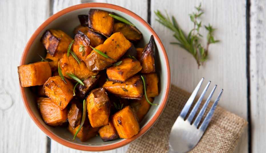 oven roasted sweet potatoes with thyme and rosemary in a bowl
