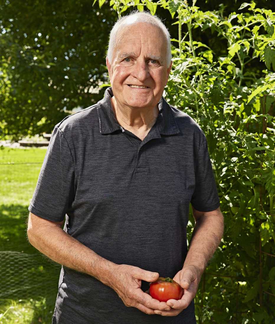 tim cronin stands in his garden holding a tomato