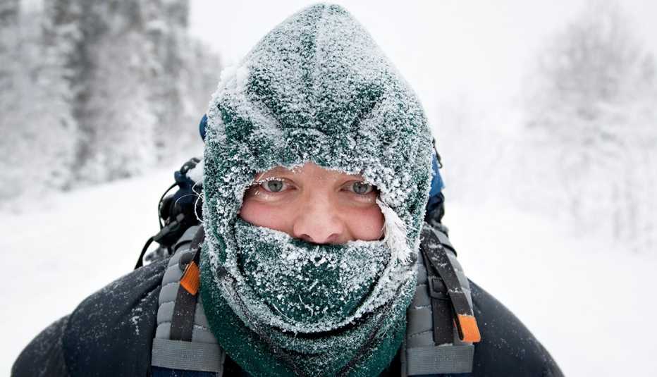 man in a snowy scene with a facemask and scarf covering his mouth
