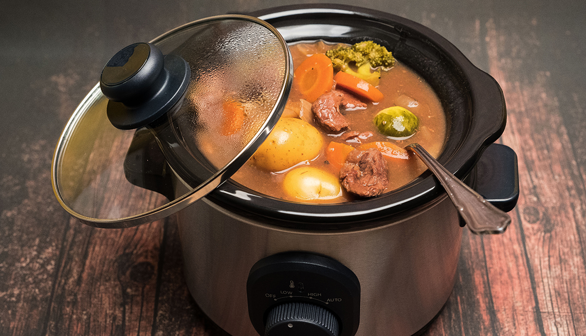 beef casserole and vegetables cooked in a slow cooker on a wooden table that could lead to foodborne illness due to improper temperatures and cooking methods