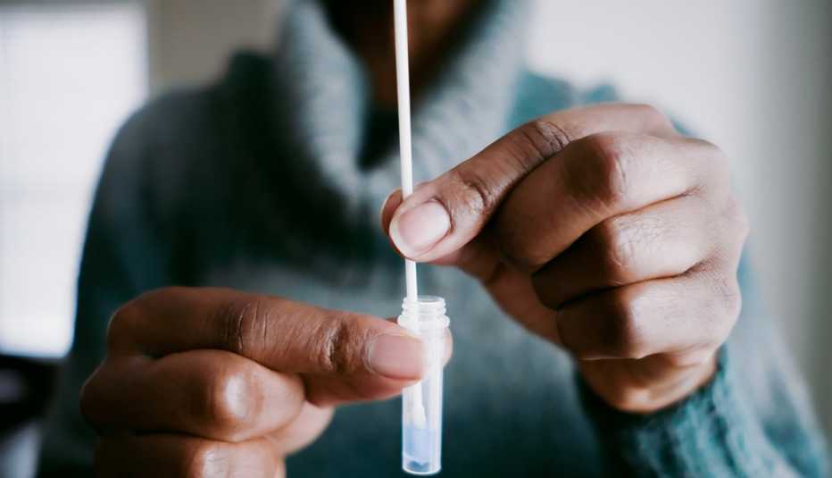 Close up of an African American woman swirling a nasal swab in reagent solution for an at-home COVID-19 test
