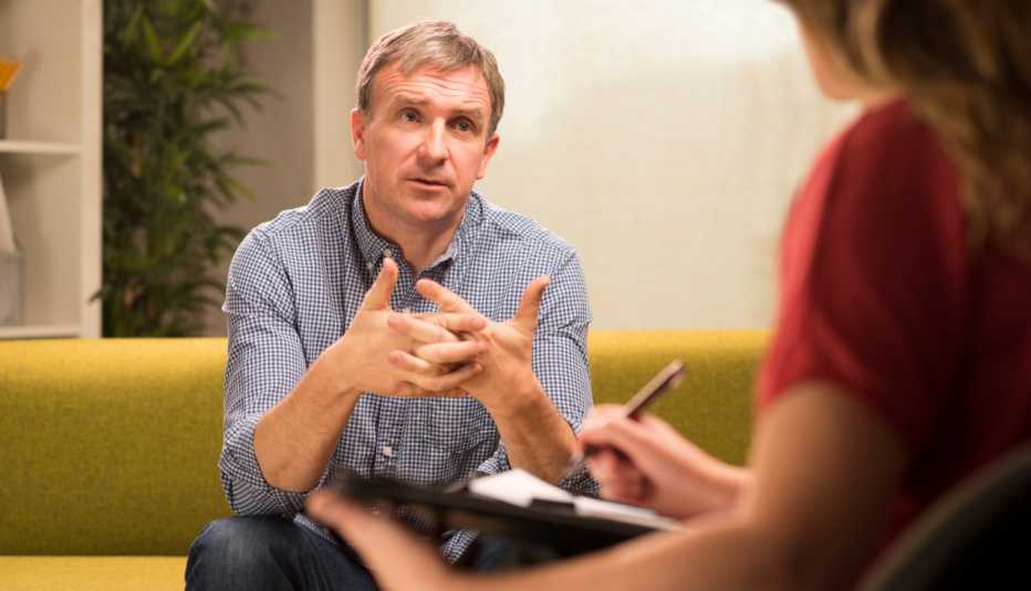 a man talks to a female therapist holding a clipboard and pen