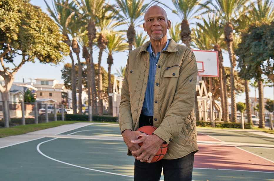 Kareem Abdul-Jabbar poses on an outdoor community basketball court