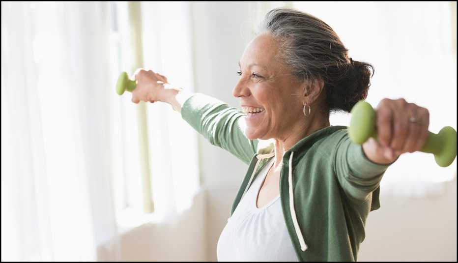 Older Hispanic woman lifting weights in living room
