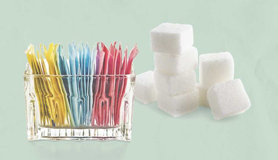 artificial sweeteners in a clear glass container and a stack of sugar cubes