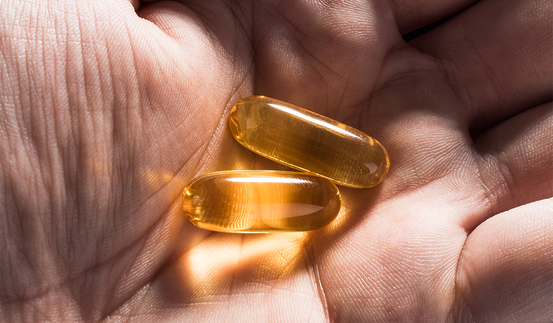 Close up of hand holding two vitamin pills