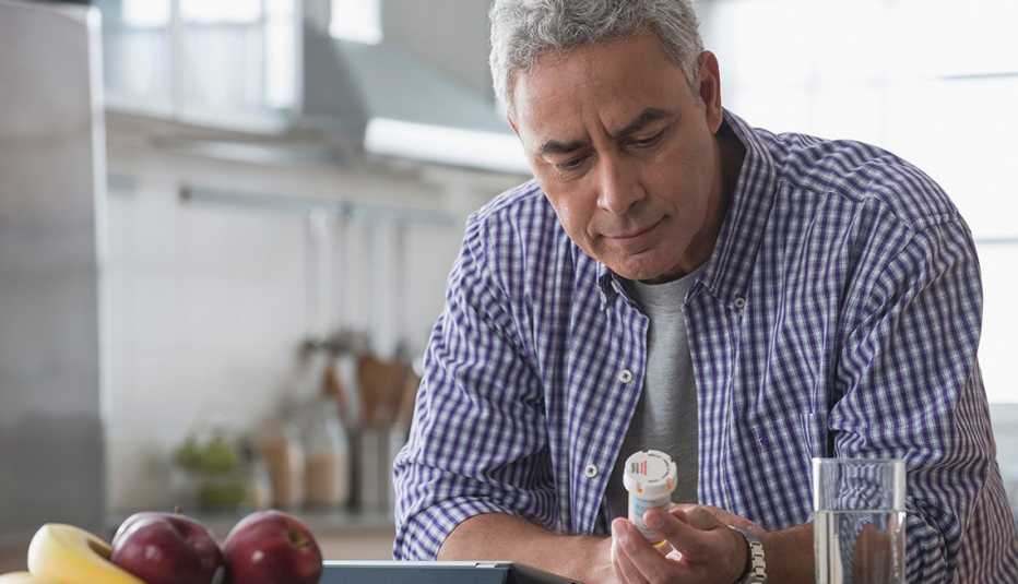 A man examining a prescription drug bottle in the kitchen