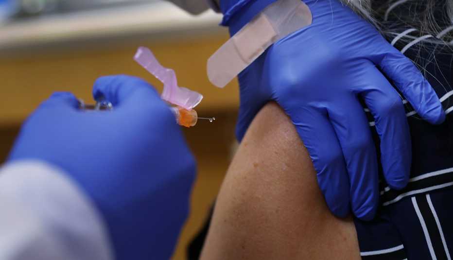 Gloved hands giving a flu shot in a patient's arm