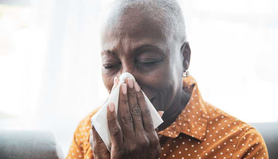 woman sneezing into a tissue 