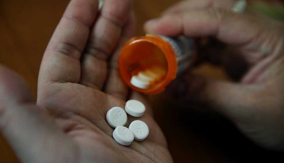 pills from a prescription bottle in a man's hand