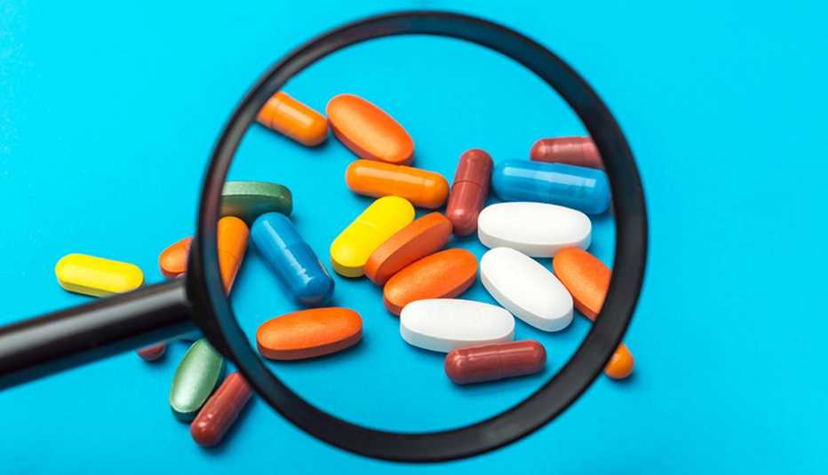 close up of a magnifying glass with multi-colored supplements and over-the-counter medications that are riskier after 50