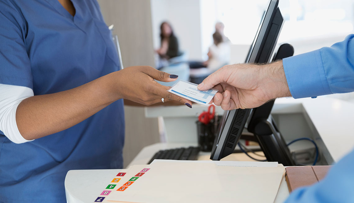 a man handing an insurance card to a nurse