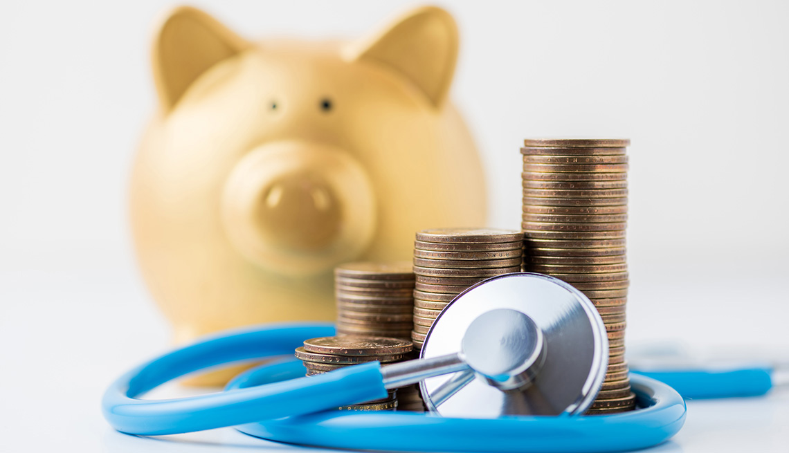 A coin stack with stethoscope and gold piggy bank on white background.