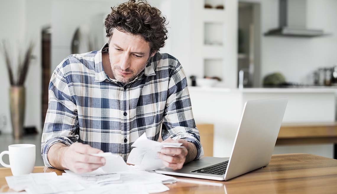 A man is reading bills while making online payment at home