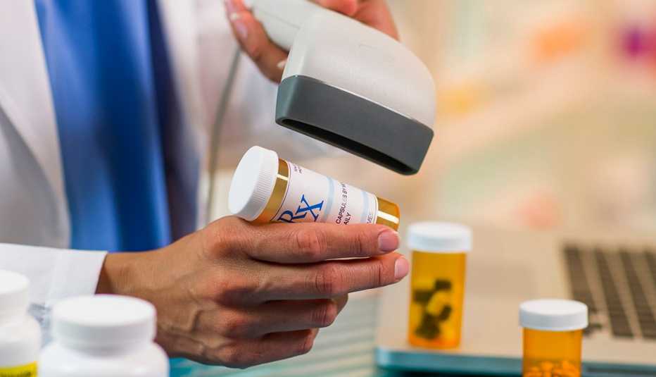 Closeup of pharmacist scanning prescription drug bottle at cash register