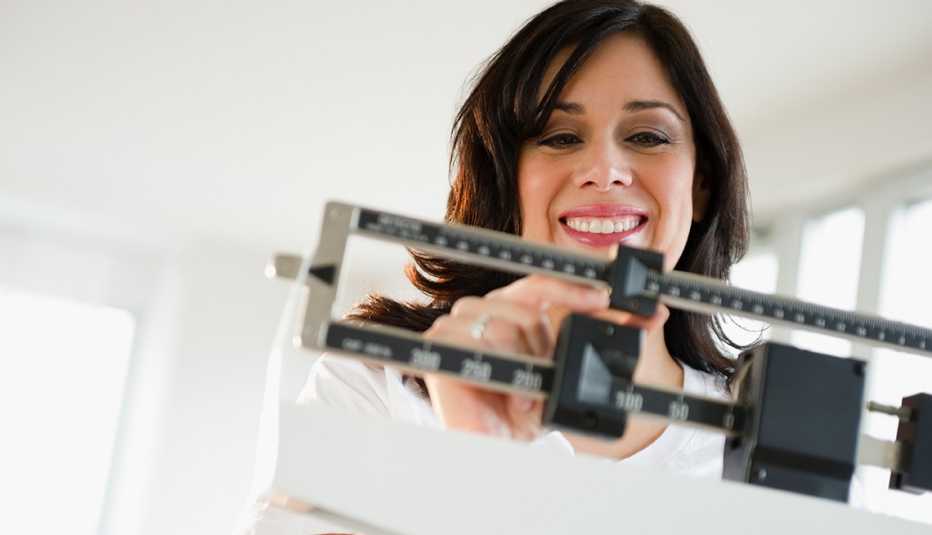 Woman adjusting weight on scale
