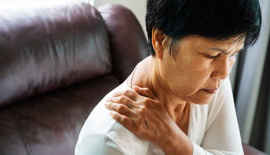 Mature Asian American woman suffering from neck pain. 