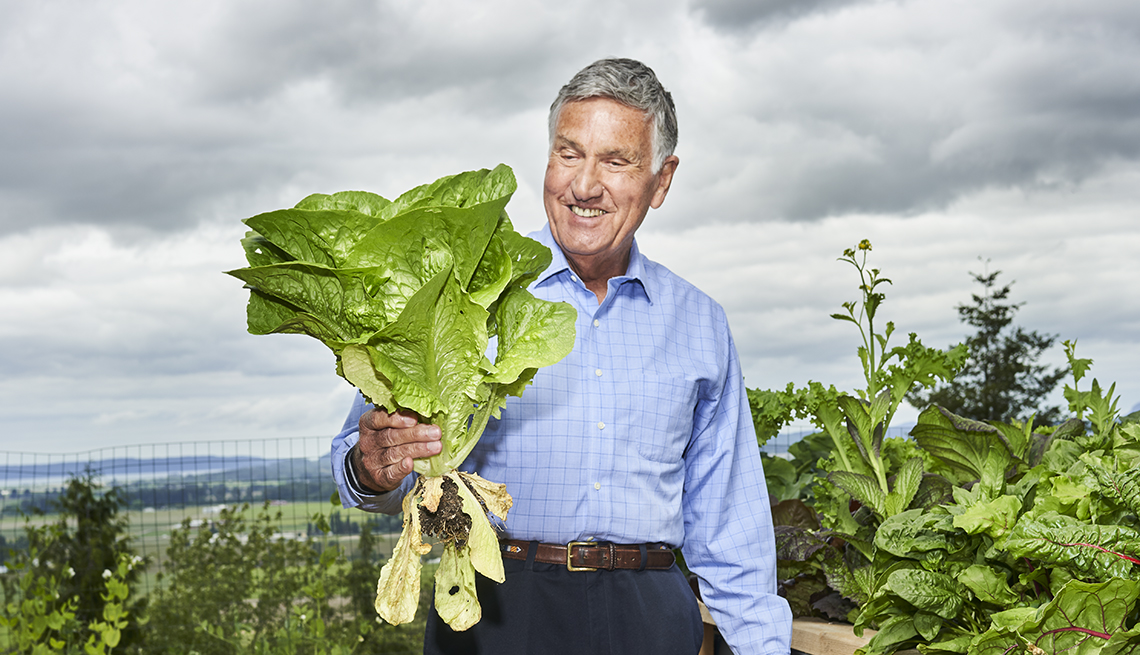 Graham Kerr, The Galloping Gourmet, standing outside on a farm, holding some greens. 