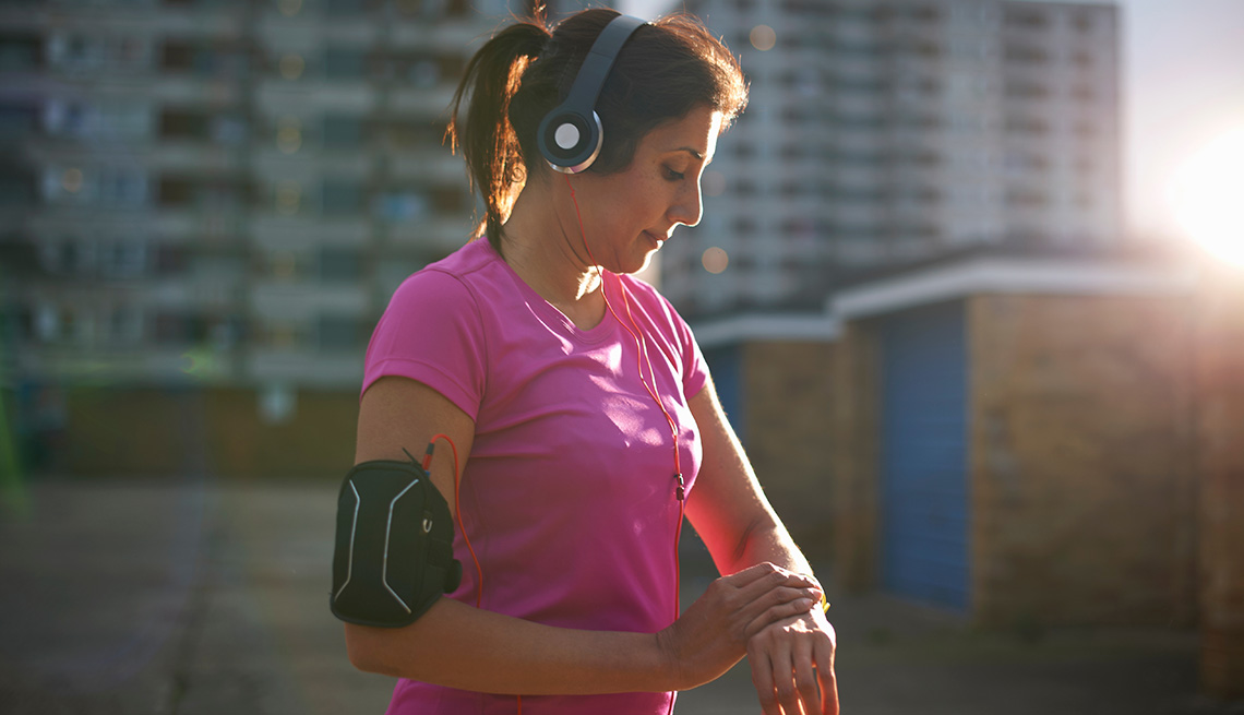 Woman outside in an urban setting, checking her watch during her workout. 