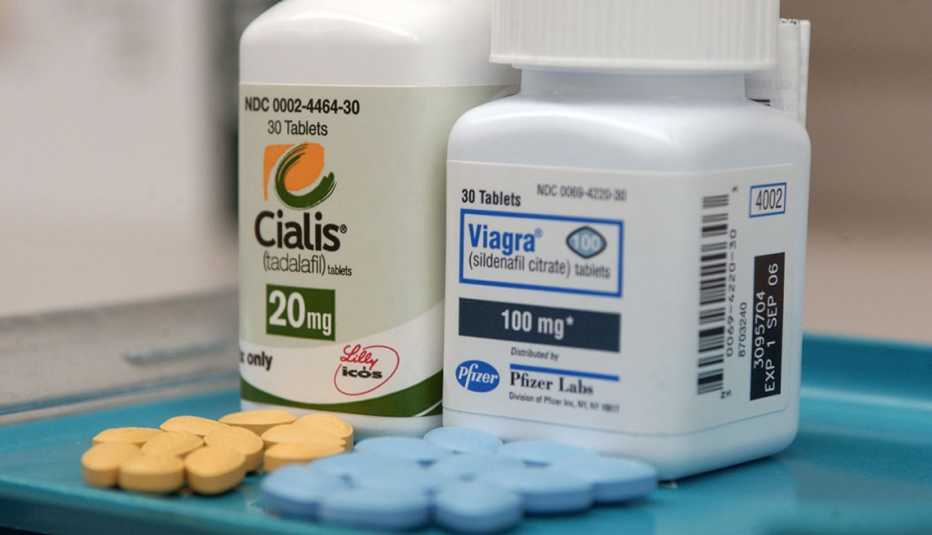 Cialis and Viagra pill bottles with pills on a tray.