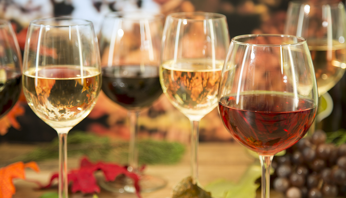 Outdoor fall setting with multiple glasses of wine sitting on a table.