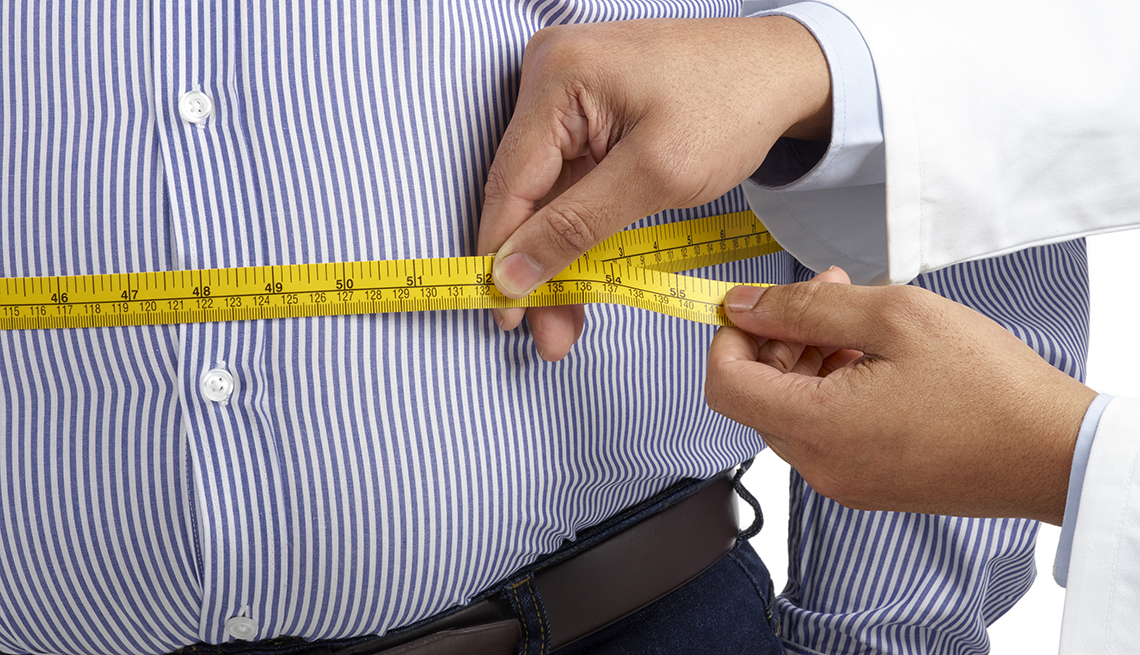 doctor measuring overweight man's waist