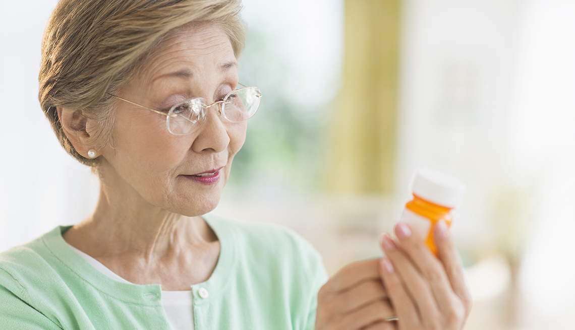 A woman reading the label on a prescription pill bottle