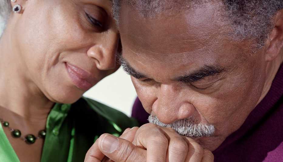 Older African American man kissing an older African American woman's hand in a loving gesture
