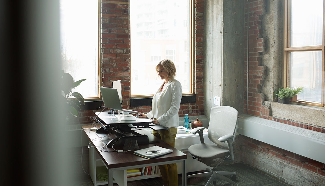 Businesswoman using computer sit-stand desk in office
