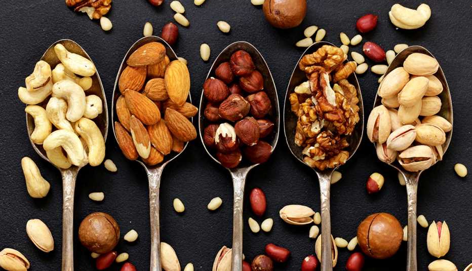 various kinds of nuts, including cedar, cashew, hazelnuts, walnuts, in spoons