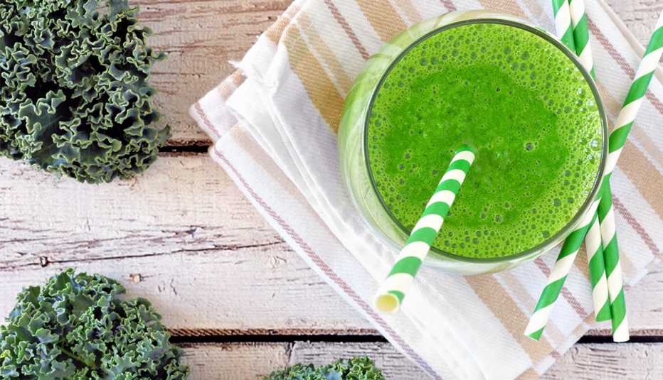 Green kale smoothie with straws overhead view