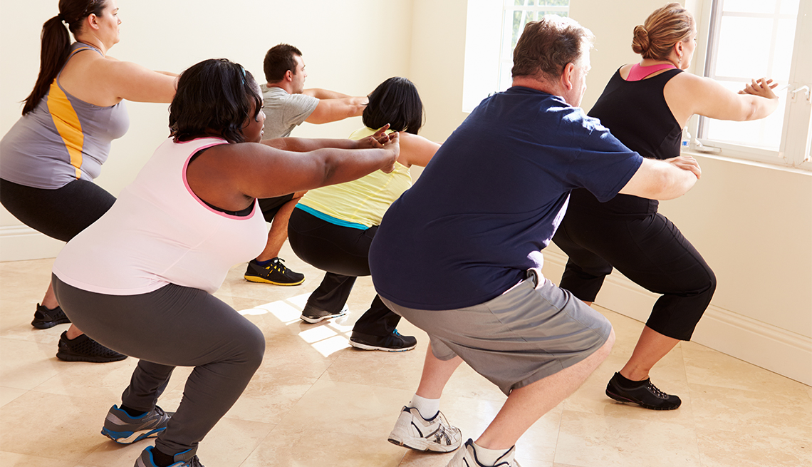 Fitness Instructor In Exercise Class For Overweight People Doing Squats 