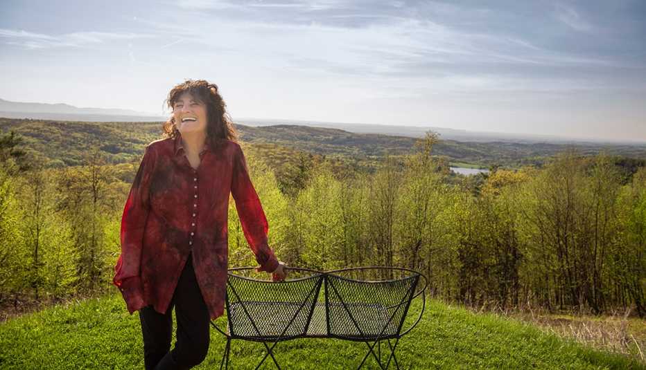 ruth reichl stands on a hilltop overlooking mountains and a river in her yard