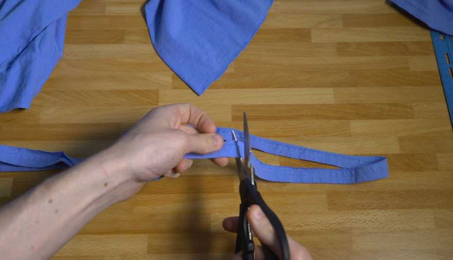 Scissors cutting through strip of a cotton t-shirt.