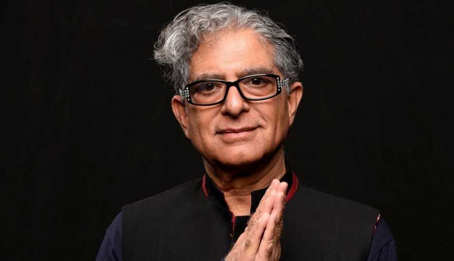 deepak chopra looking at the camera holding up his hands with the palms pressed together
