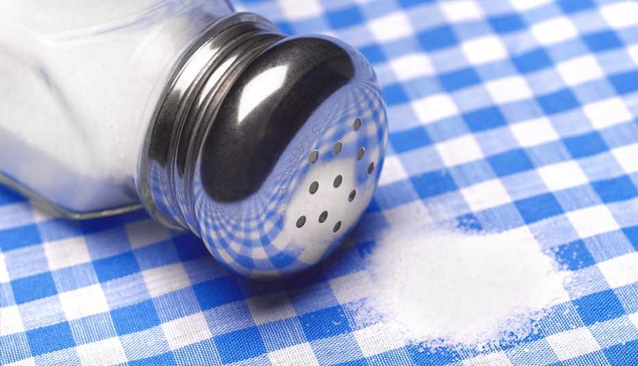 Close up a salt shaker and salt on a table