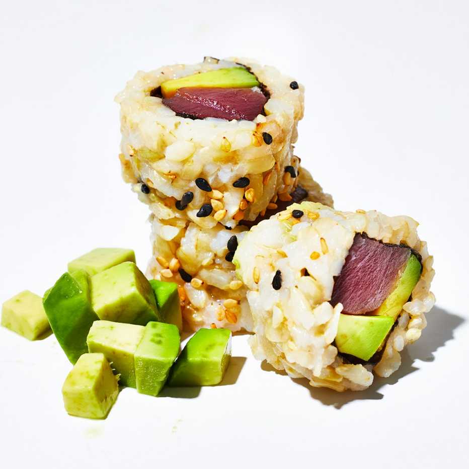 closeup of a few slices of a sushi tuna roll with brown rice and avocado
