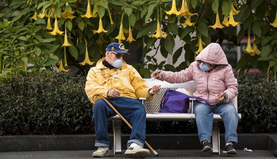 People wearing protective masks use hand sanitizer while sitting in Union Square in San Francisco, California, U.S., on Wednesday, March 4, 2020. 
