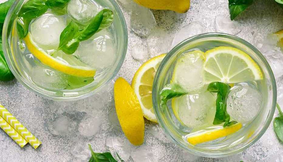 two glasses of summery looking lemonade with herb leaves and lemon slices overhead shot