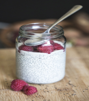 a short mason jar of chia pudding with raspberries