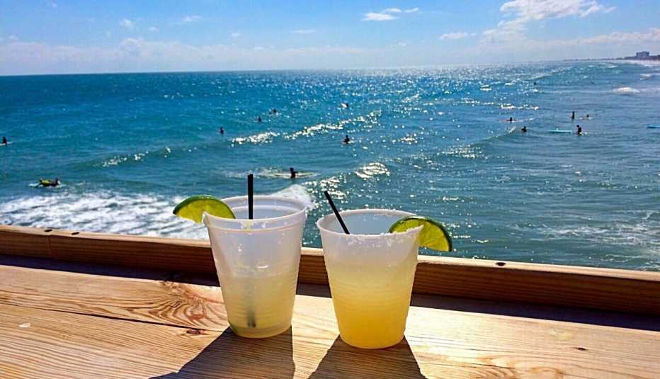 mixed drinks sitting on a wood bar overlooking the ocean on a bright summer day