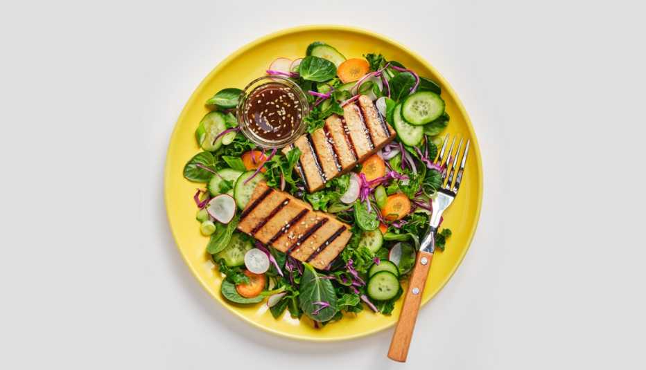 a plate of grilled tofu on top of a salad