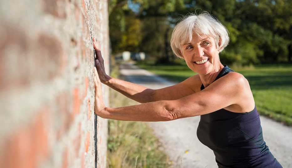 woman doing a pushup off of a brick wall outside