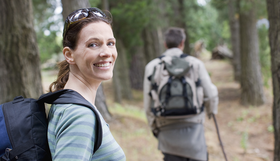 couple hiking in the woods, woman smiling at the camera