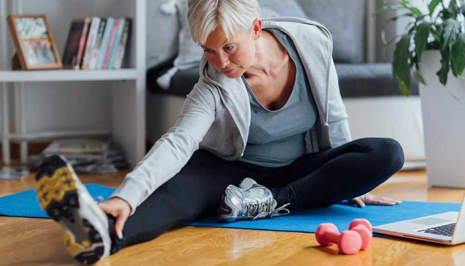 mature woman exercising at home on a yoga mat doing a stretch