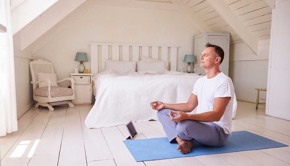 Meditation app concept - man meditating with tablet