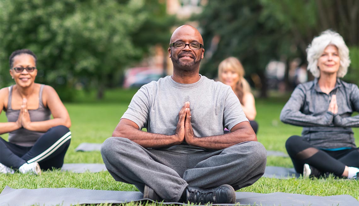 A multi-ethnic group of seniors is attending a yoga class outdoors