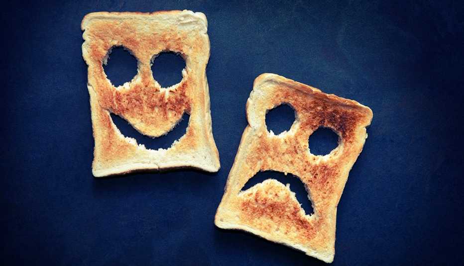 Two slices of toasted bread with happy and unhappy faces cut out
