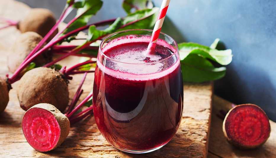 Glass of beet juice surrounded by beets.