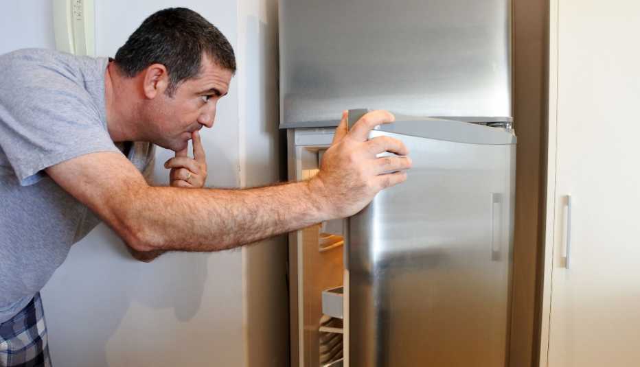 man wearing pjs looks in the fridge for something to eat